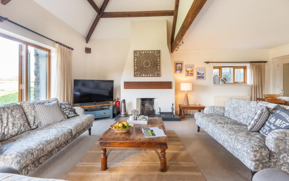 Large sitting area with high ceiling, exposed beams and open fire at Blackness Barn