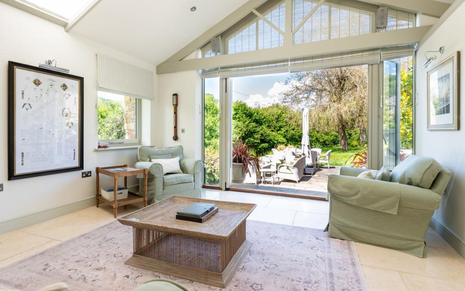 Sunroom with comfy seating and big patio doors out to the rear patio and garden at Bow Bridge House 