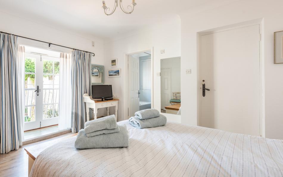 master bedroom with balcony at 1 Kings Cottages