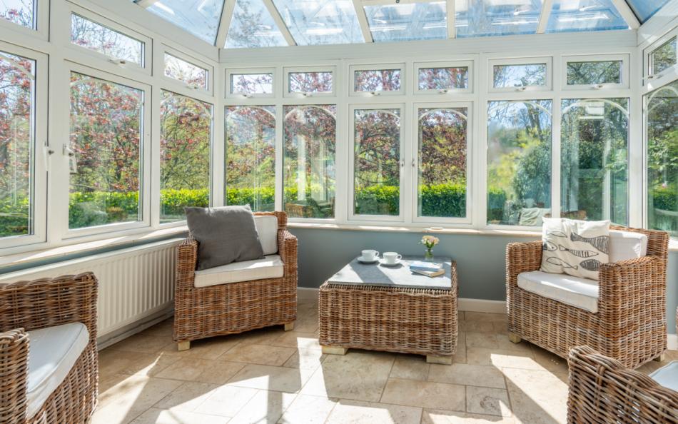 The sun room surrounded by the pretty lawned garden at Clover Cottage