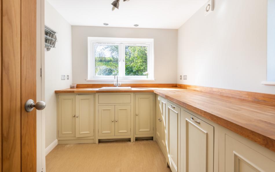 Utility room with freezer, washing machine and tumble dryer, drying rack and sink at Clover Cottage